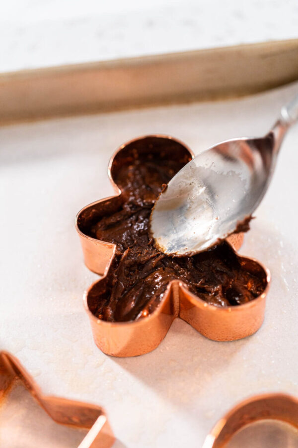 Filling cookie cutter with fudge mixture to prepare Christmas cookie-cutter peppermint fudge.