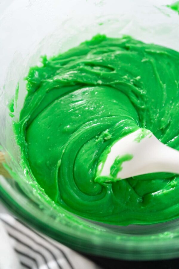 Melting chocolate chips and other ingredients in the double boiler to prepare green fudge with red hearts.