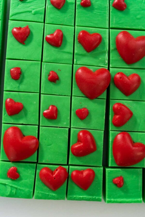 Flat lay. Homemade green fudge with red hearts square pieces on a kitchen counter.