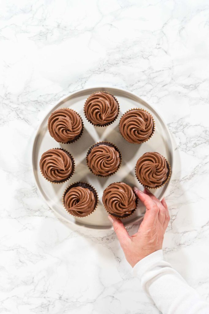 Baked chocolate cupcakes topped with piped swirls of chocolate frosting