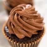 Close-up of single chocolate cupcake topped with a perfect swirl of piped frosting.