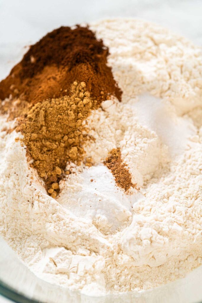 Bowl with flour, ground ginger, cinnamon, and cloves combined as the dry ingredients for Vibrant Green Gingerbread Cookies for Festive Baking. These spices create the classic gingerbread aroma.