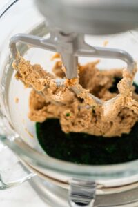 The creamed butter and sugar mixture being combined with the vibrant green maple syrup blend in the mixer for Vibrant Green Gingerbread Cookies for Festive Baking.