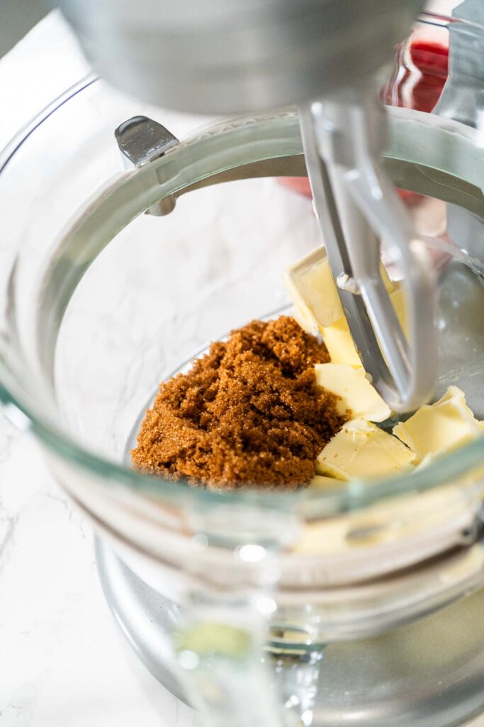 A close-up of cubed butter and packed brown sugar in a mixing bowl, ready for creaming. These ingredients will create the tender, chewy texture in the Classic Red Gingerbread Dough.