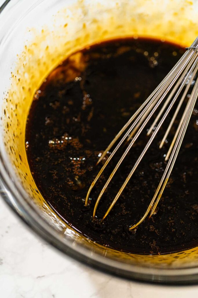A bowl filled with molasses and two large eggs for Spiced Gingerbread Cookie Dough Perfect for Baking. The dark molasses contrasts with the bright yolks, creating a rich base for the dough.