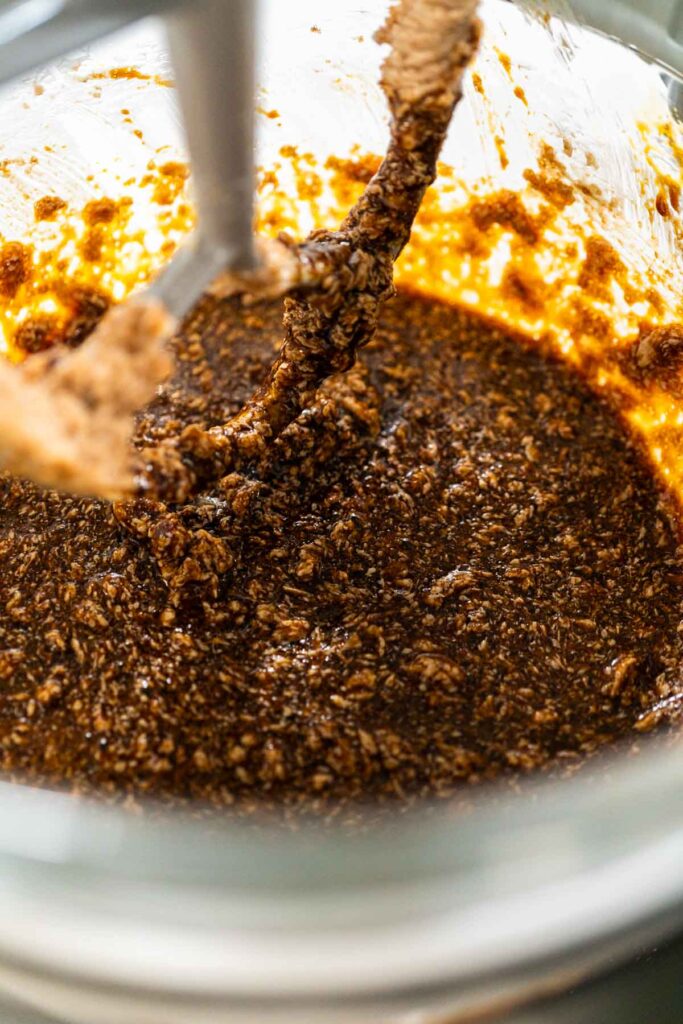 Top-down view of a stand mixer blending molasses into the butter-sugar mixture, creating a rich base for Spiced Gingerbread Cookie Dough Perfect for Baking. The mixture is smooth and dark, building depth for the dough.
