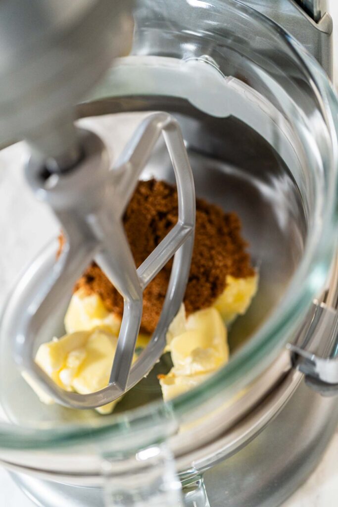 Cubed butter and brown sugar in a stand mixer bowl for Zesty Orange Gingerbread Cookie Dough. These ingredients will be creamed to create a smooth, rich base for the cookie dough.