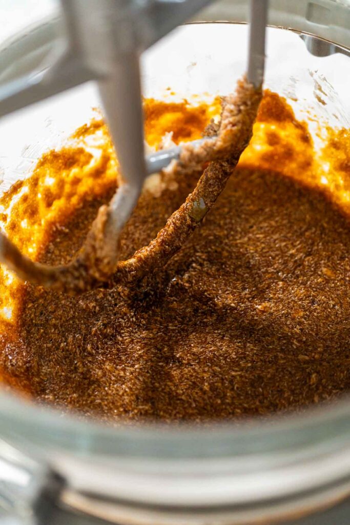 Molasses mixture blending with butter and sugar in a stand mixer for Zesty Orange Gingerbread Cookie Dough. The rich, dark molasses combines smoothly with the creamed ingredients, adding depth to the dough.