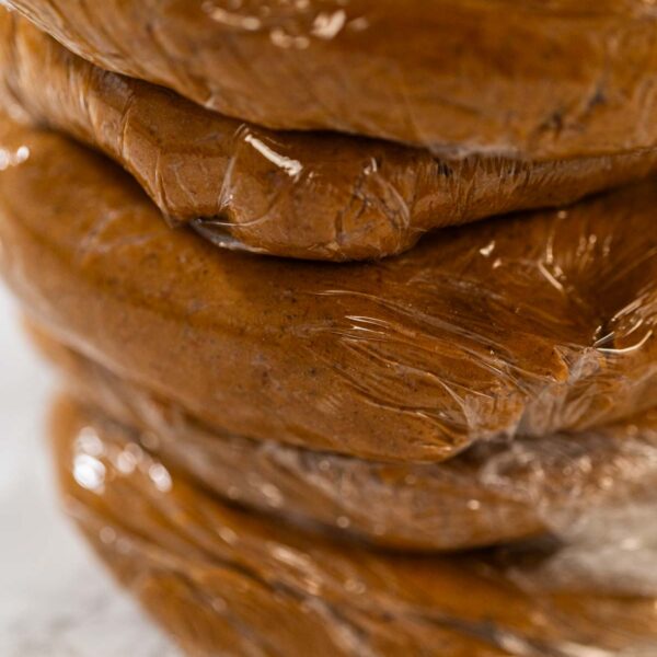 Zesty Orange Gingerbread Cookie Dough for Baking - Arina Photography Portions of Zesty Orange Gingerbread Cookie Dough wrapped in plastic wrap and stacked, ready for chilling. Dividing the dough ensures easier handling when rolling out and cutting shapes later.