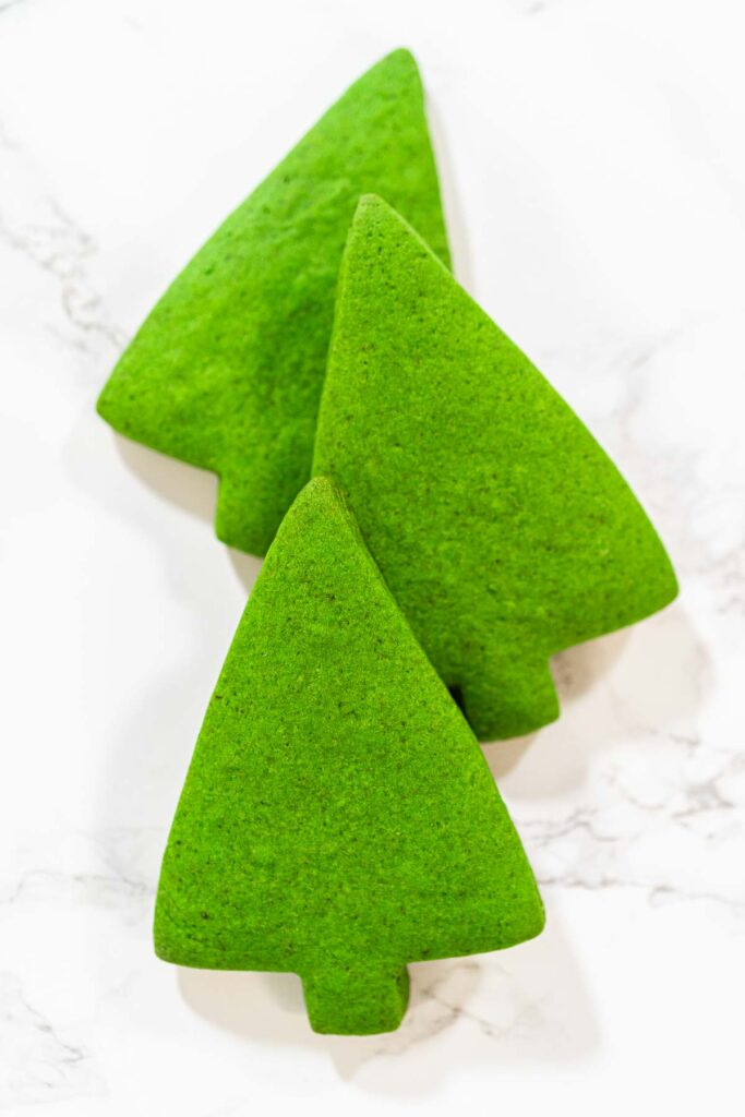 Three Green Gingerbread Cookies are arranged together in a standing formation, displaying their festive Christmas tree shape and vivid green color.