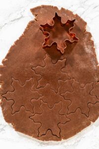 Chocolate Ginger Sugar Cookies in Snowflake Shapes A Festive Tre - Arina Photography A close-up of snowflake-shaped cookie cutters pressed into Chocolate Ginger Sugar Cookie dough, capturing the intricate details of the shapes.