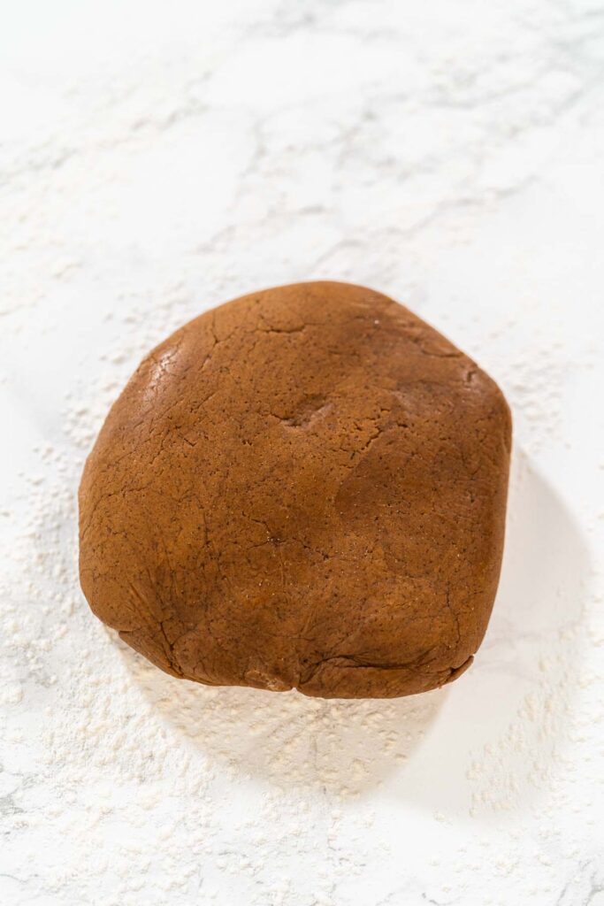 Step-by-Step Process of Making Spiced Gingerbread Cookies - Arina Photography Straight-on view of a ball of spiced gingerbread cookie dough placed on a marble countertop, ready for rolling and shaping.