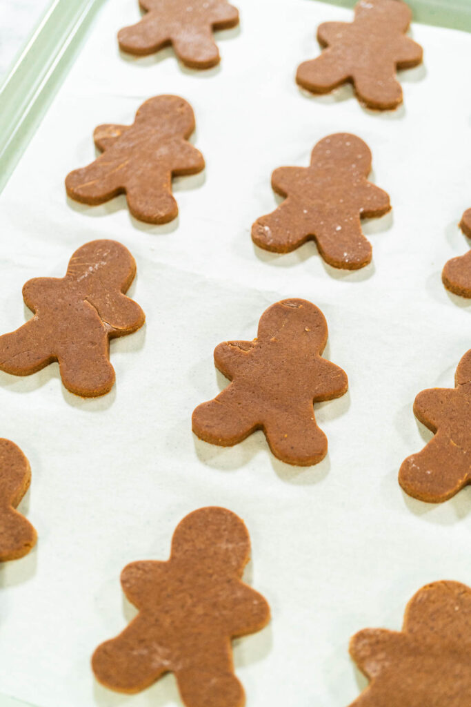 Step-by-Step Process of Making Spiced Gingerbread Cookies - Arina Photography Close-up view of a single gingerbread man cookie on parchment paper, highlighting its festive design and baked finish.