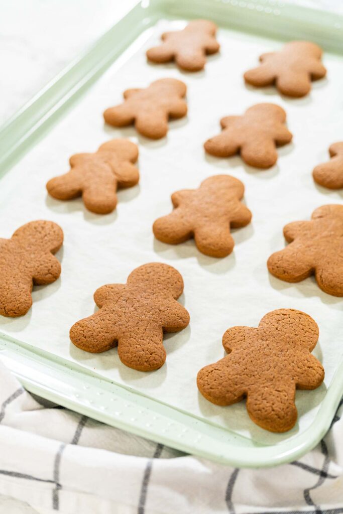 Step-by-Step Process of Making Spiced Gingerbread Cookies - Arina Photography Straight-on view of a cooling rack with freshly baked gingerbread man cookies, showcasing the festive design and even baking.