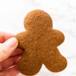 Close-up view of a hand holding a Spiced Gingerbread Cookie, highlighting its festive holiday design and even baking.