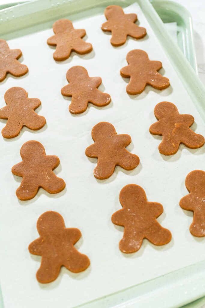 Preparing and Baking Classic Gingerbread Cookies in Gingerbread - Arina Photography Angled view of unbaked gingerbread man cookies evenly arranged on a parchment-lined baking sheet.
