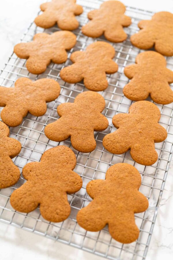 Close-up of golden-brown gingerbread men with heart-shaped cutouts cooling on a wire rack.