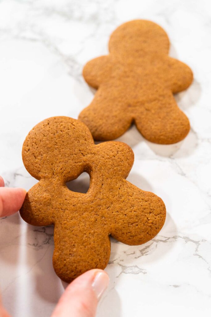 Preparing and Baking Classic Gingerbread Cookies in Gingerbread - Arina Photography Close-up of a single gingerbread man cookie with a heart-shaped cutout on a white surface.