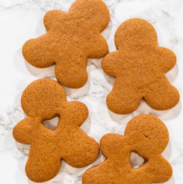 Preparing and Baking Classic Gingerbread Cookies in Gingerbread - Arina Photography A hand holding a gingerbread man cookie with a heart-shaped cutout, close-up view.