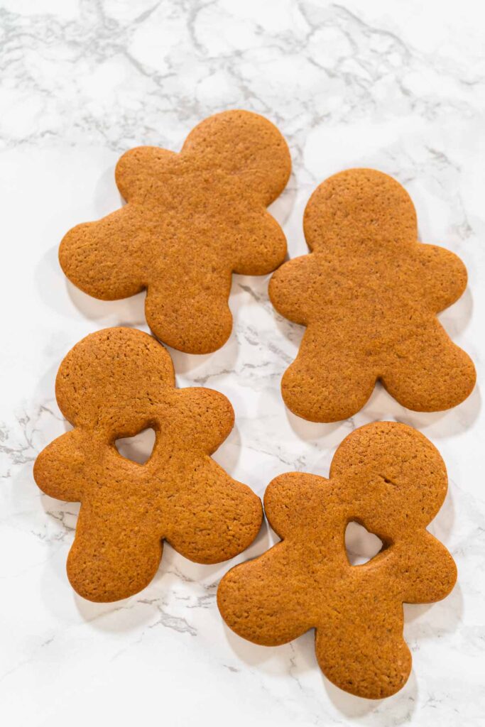Preparing and Baking Classic Gingerbread Cookies in Gingerbread - Arina Photography A hand holding a gingerbread man cookie with a heart-shaped cutout, close-up view.