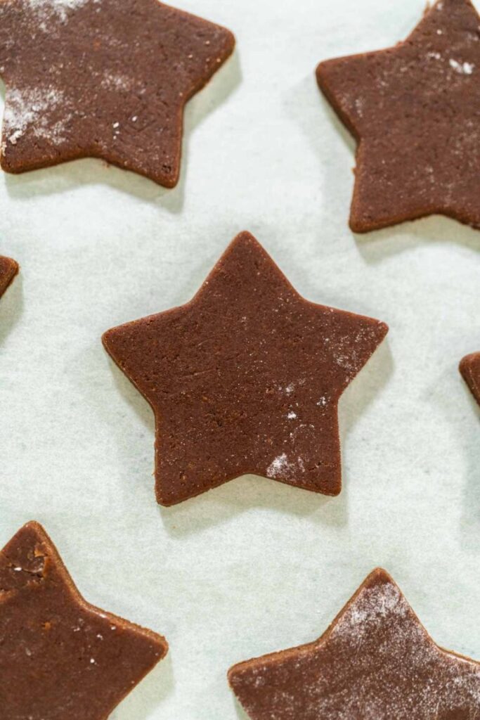 Baked star-shaped chocolate-spiced gingerbread cookie cooling on parchment paper.