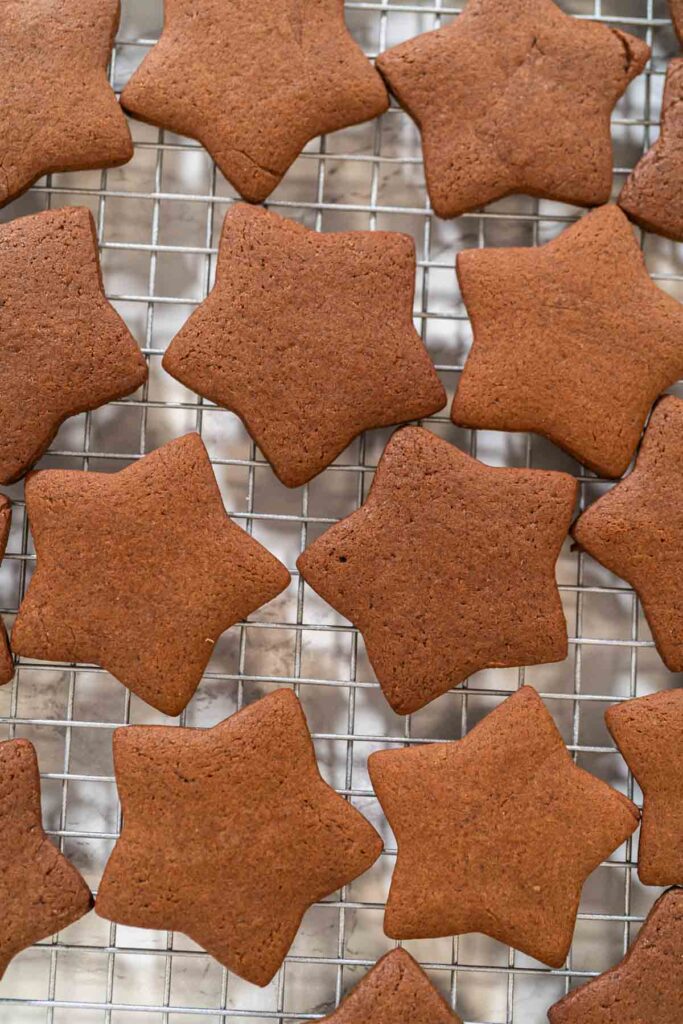 Freshly baked star-shaped chocolate-spiced gingerbread cookies cooling on a wire rack.