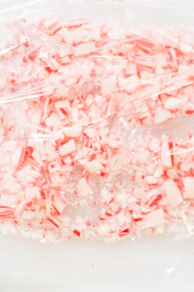 Crushed candy canes in a clear plastic bag for baking, showing fine and chunky peppermint pieces.