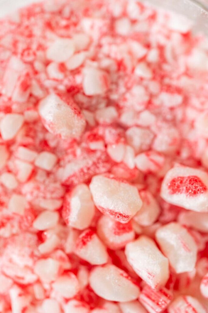 Close-up of crushed peppermint candy cane pieces, showing red and white chunks ready for holiday baking.
