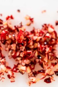 Close-up of freshly diced cranberries on a cutting board, showing small red and white pieces ready for baking or cooking.