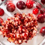 835-05000 - Arina Photography Close-up of freshly diced cranberries in a glass bowl with whole cranberries scattered around, showing the vibrant red fruit pieces ready for baking or cooking.
