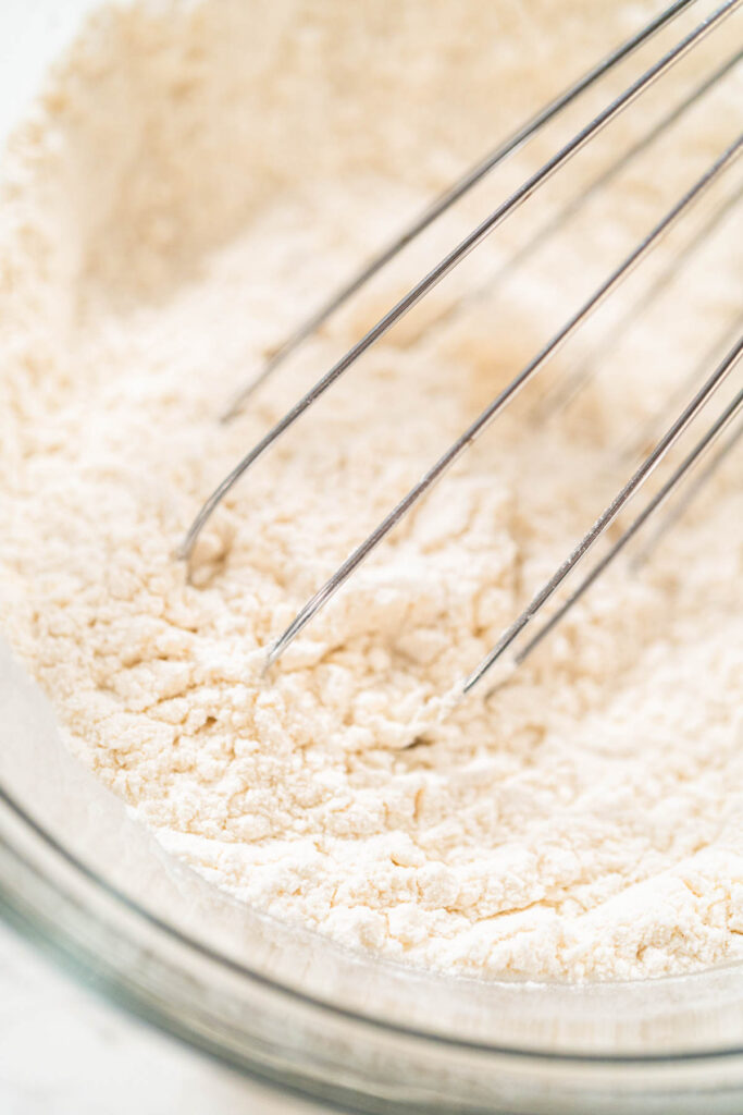 Whisk blending flour mixture in a glass bowl for lemon spritz cookie dough.