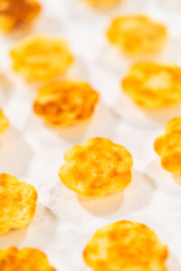 Baked lemon spritz cookies placed upside down on parchment paper, showing their golden browned bottoms.