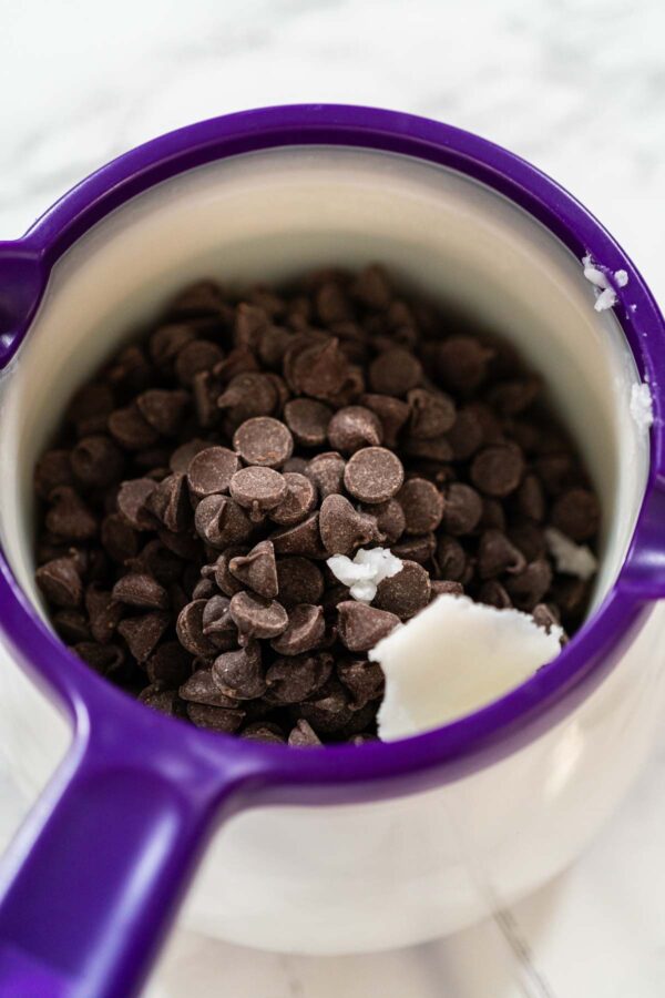 Dark chocolate chips and coconut oil in a purple melting pot, ready to be melted for dipping sugar cookies.