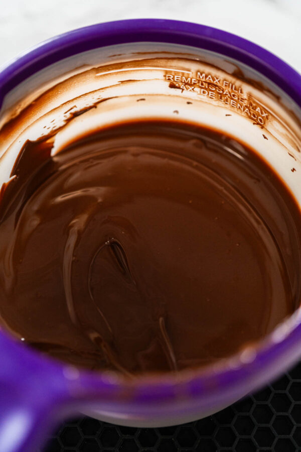 Melted dark chocolate combined with coconut oil in a Wilton Candy Melting Pot, ready for dipping holiday sugar cookies.