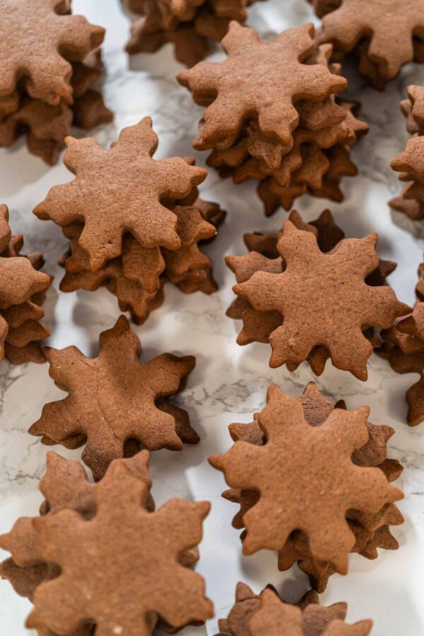 Stacked chocolate snowflake cookies with crisp edges, perfect for decorating with royal icing or serving plain as festive holiday treats.