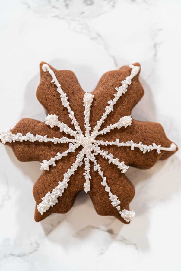 Close-up of a chocolate snowflake cookie decorated with white royal icing and sparkling sugar crystals, ideal for winter-themed holiday treats and Christmas dessert tables.