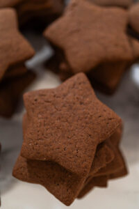 Stack of plain chocolate star cookies made from chocolate gingerbread dough, perfect for holiday decorating or gifting.